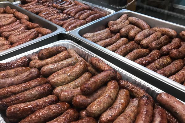 Large pans of cooked brats